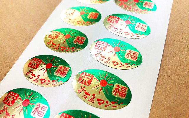 マンゴーに直貼りするブランドシール（艶金ホイル／強粘着／4色印刷